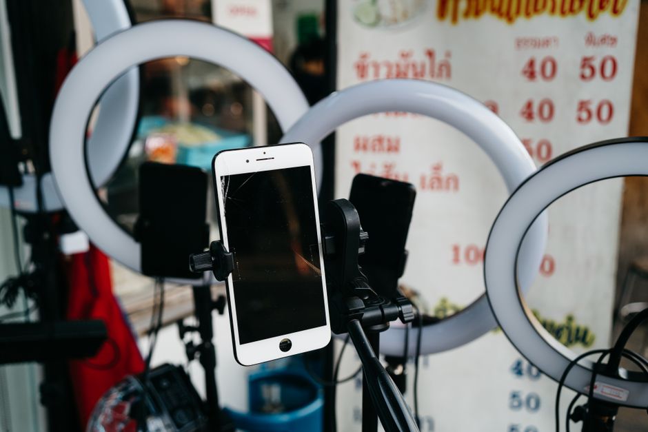 A modern smartphone mounted on a tripod surrounded by ring lights, ideal for vlogging or content creation.